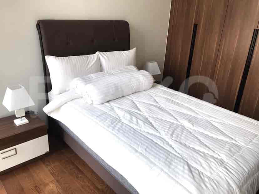 A bedroom featuring a bed, bedside table with lamp, and a TV on a media console.
