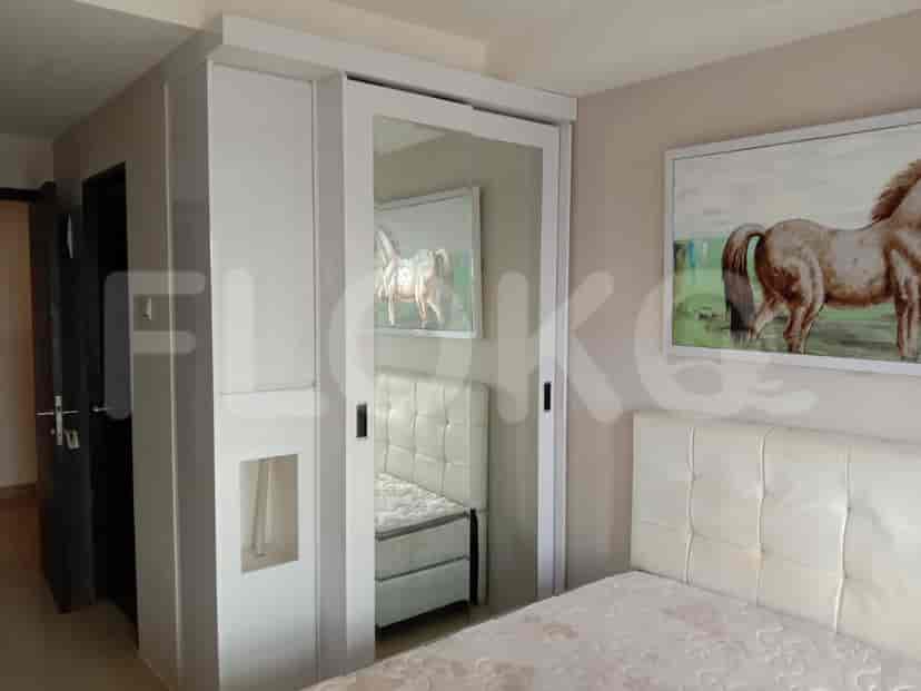 A modern bedroom with a white tufted headboard, mirrored sliding closet doors, and artwork depicting horses.