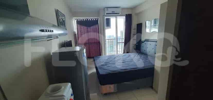 Kamar tidur kecil dengan tempat tidur, lemari pakaian dan area dapur terlihat.