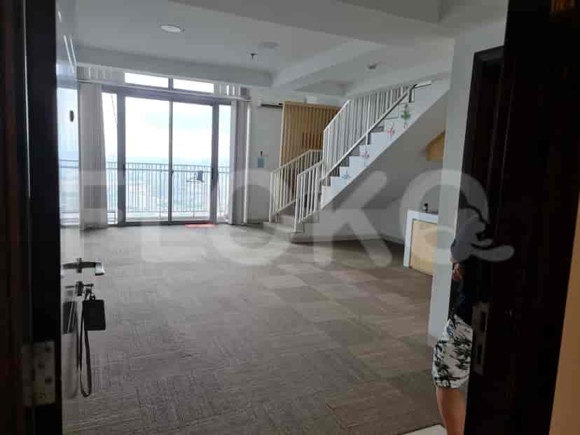 A living room with a staircase leading upstairs and a kitchen partially visible.