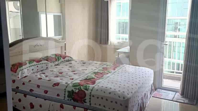 A bedroom with a bed, a window and a balcony door.