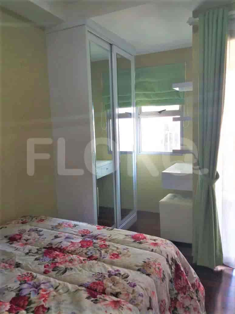 Kamar tidur kecil dengan tempat tidur bermotif bunga dan lemari pakaian dengan pintu cermin.