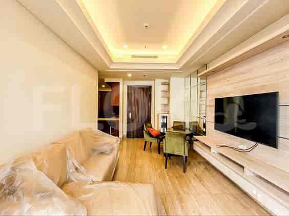 A modern living room with a sofa covered in plastic, a wall-mounted TV, and a dining area.