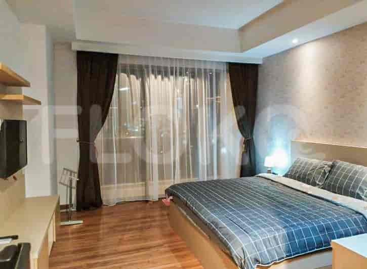 A modern bedroom featuring a bed with dark blue bedding, large windows, and wooden flooring.