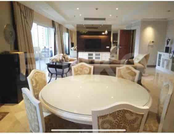 A dining area with a large round table and chairs, open to the living room, with access to a balcony.