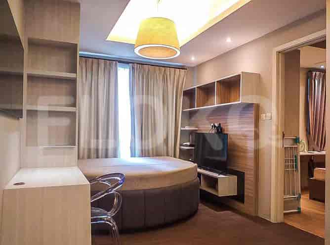 Tampilan lain dari apartemen studio dengan tempat tidur, TV, dan rak terpasang.