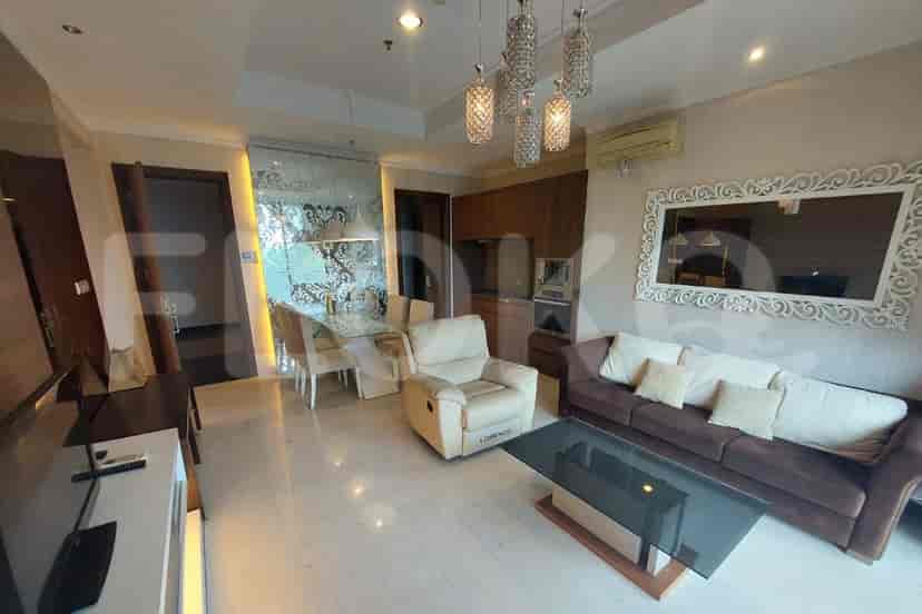 A modern living room with a dining area featuring a glass table, a sofa, and a decorative mirror.