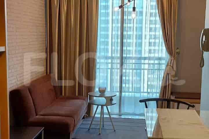 A well-lit living space featuring a velvet sofa, sheer curtains, and a view of the city.