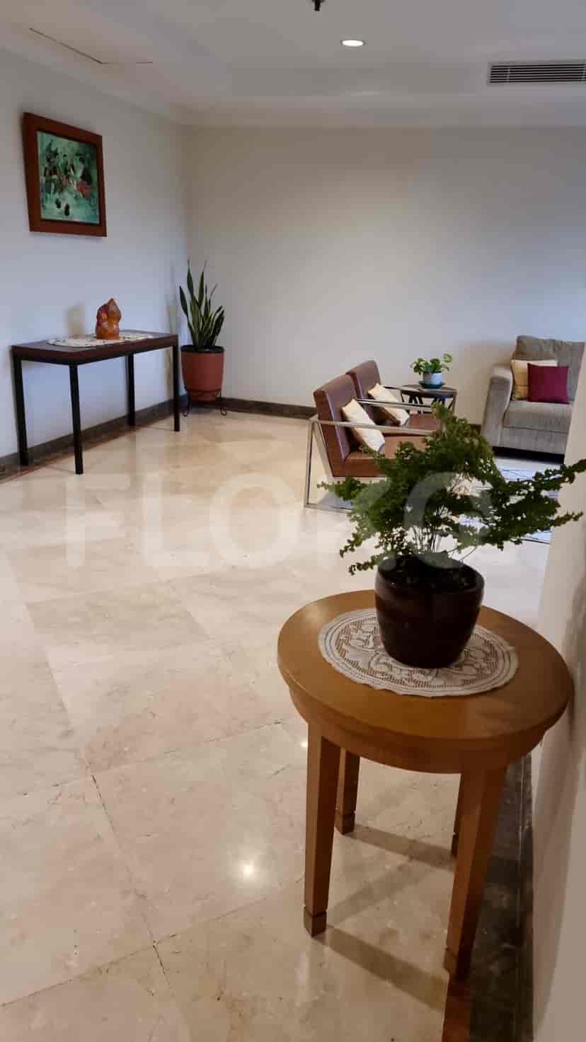 A hallway or living room with accent furniture and decorative plants.