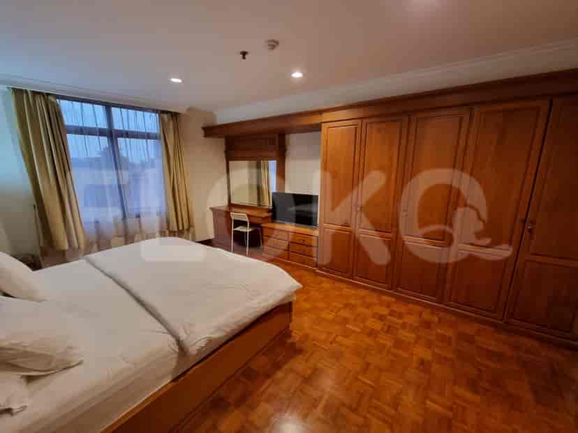 Spacious bedroom with a king-size bed, dresser, and large windows.