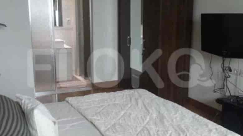 A bedroom with a double bed, a glass-door bathroom, and a large wooden wardrobe.