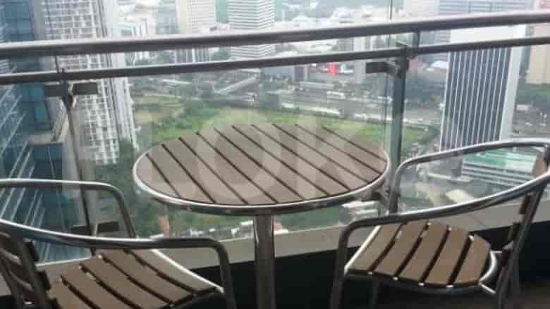 A balcony with a round table and two chairs, offering a city view.