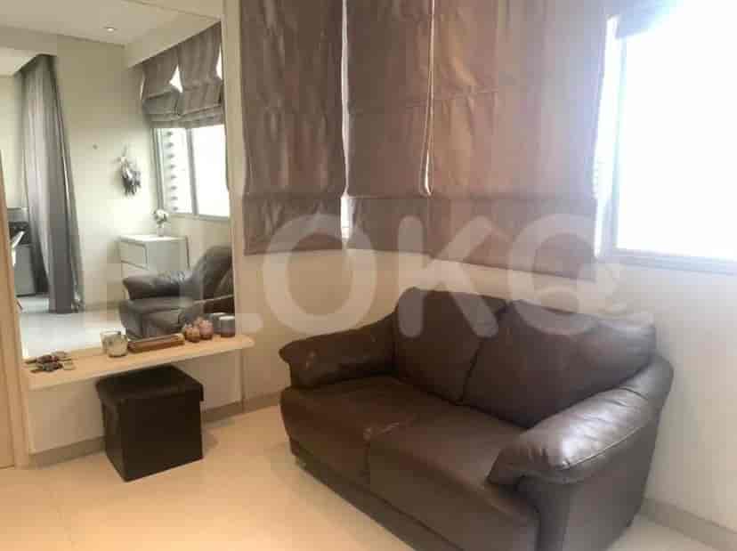 A cozy living area featuring a brown leather sofa, mirror, and ottoman.