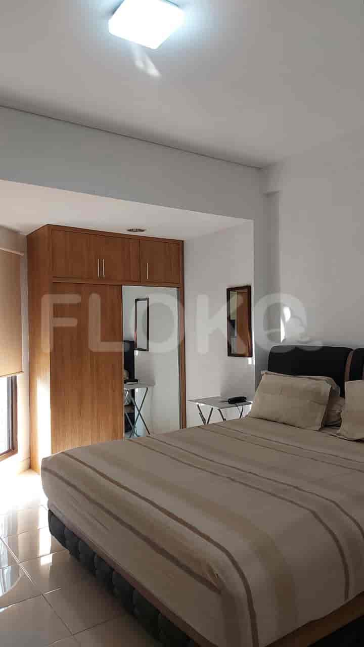 A bedroom with a wardrobe, a bed, and a window allowing natural light.
