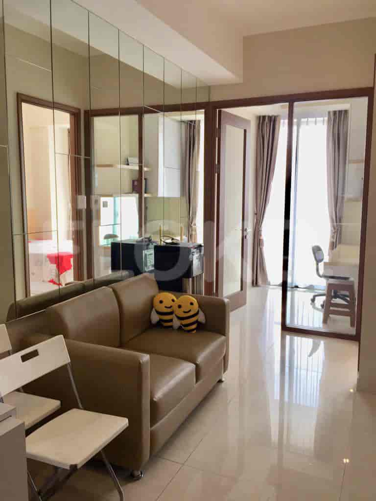 Ruang tamu yang menampilkan sofa coklat, kursi putih, dan panel dinding cermin.