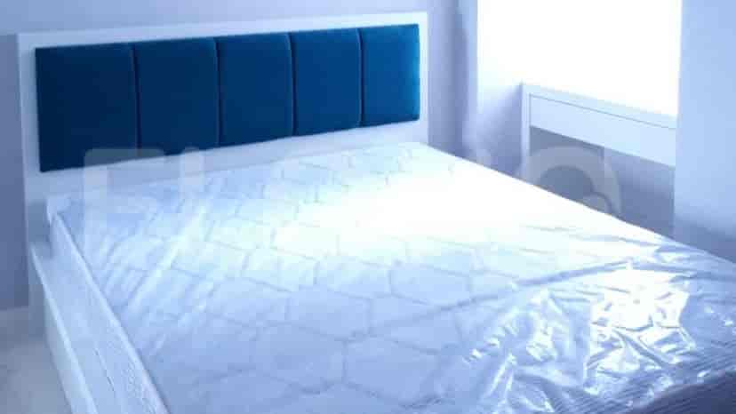 A well-lit bedroom featuring a white bed frame with a blue headboard and a mattress.
