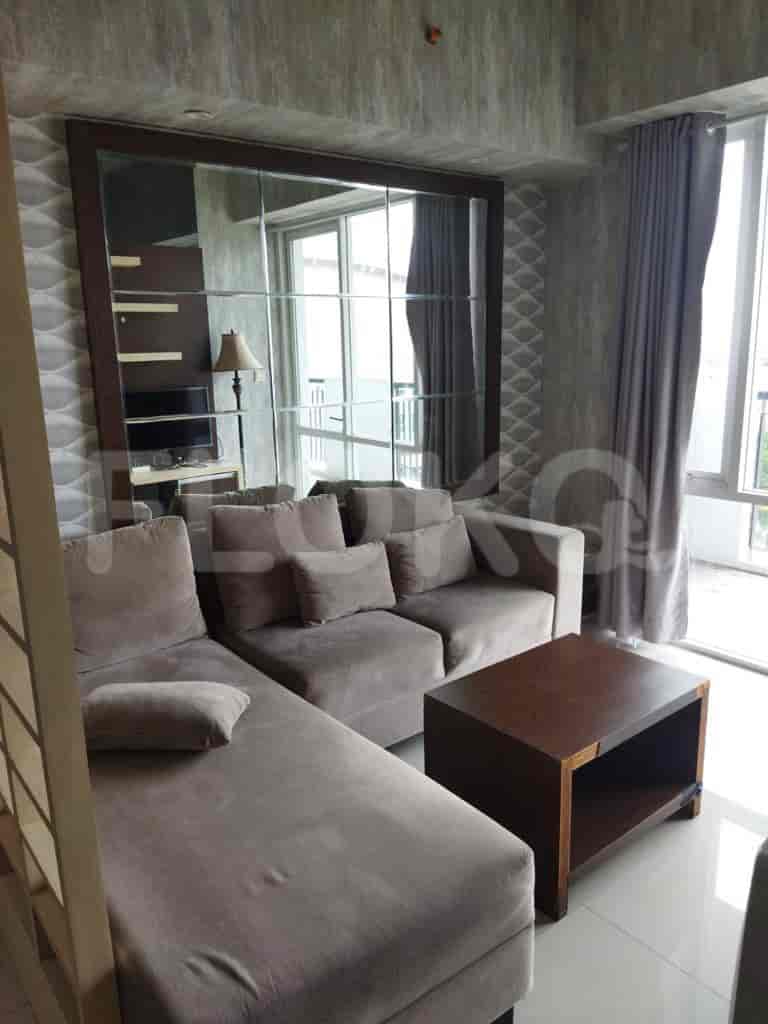 A spacious living room with an L-shaped grey sofa, mirror wall, and coffee table.