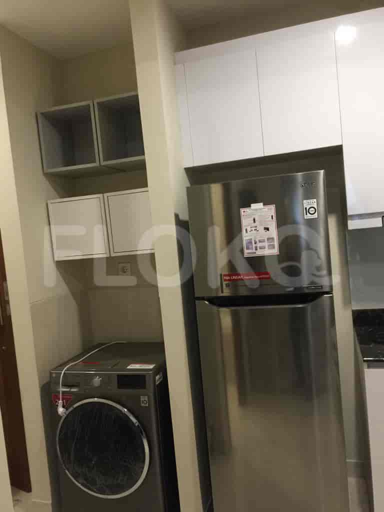 Area dapur yang ringkas dengan lemari es, lemari, dan fasilitas laundry.