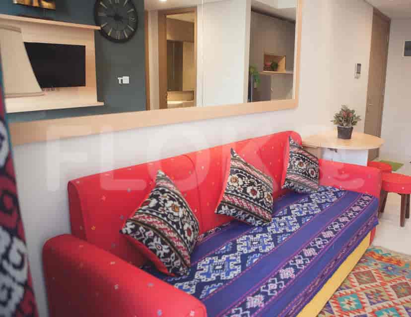 A well-lit living room featuring a red sofa, pillows, and a large mirror.