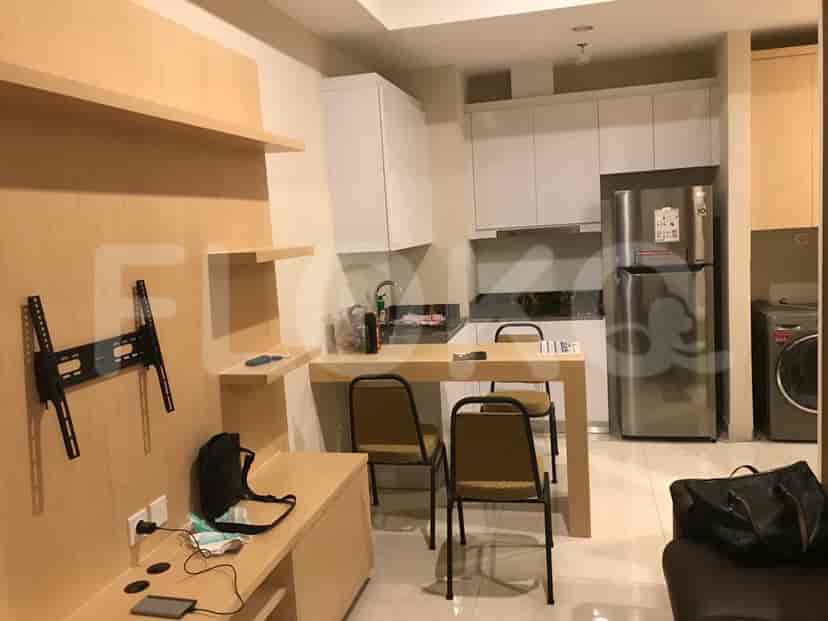 A combined living and kitchenette area with a wall-mounted TV bracket, dining table, and built-in storage.