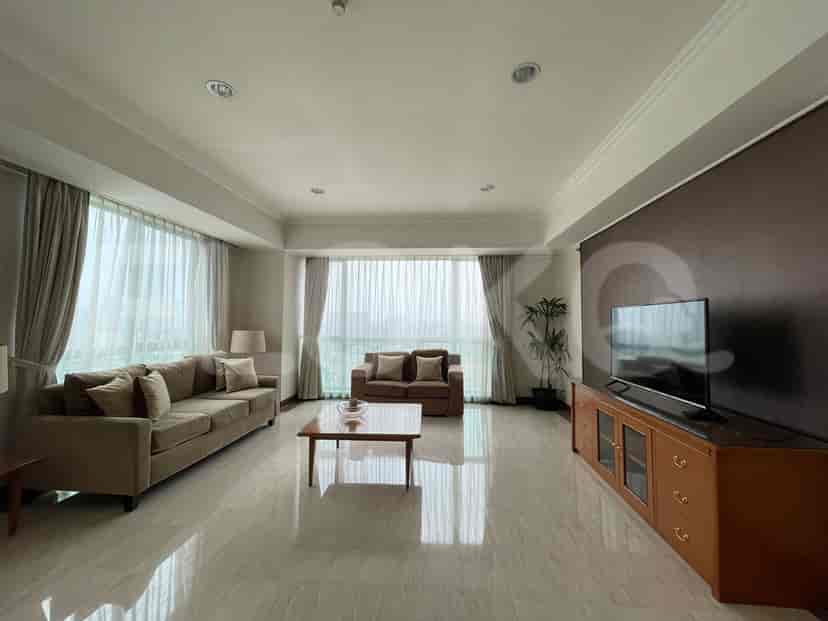 A living room with sofas, coffee table, TV, and large windows.