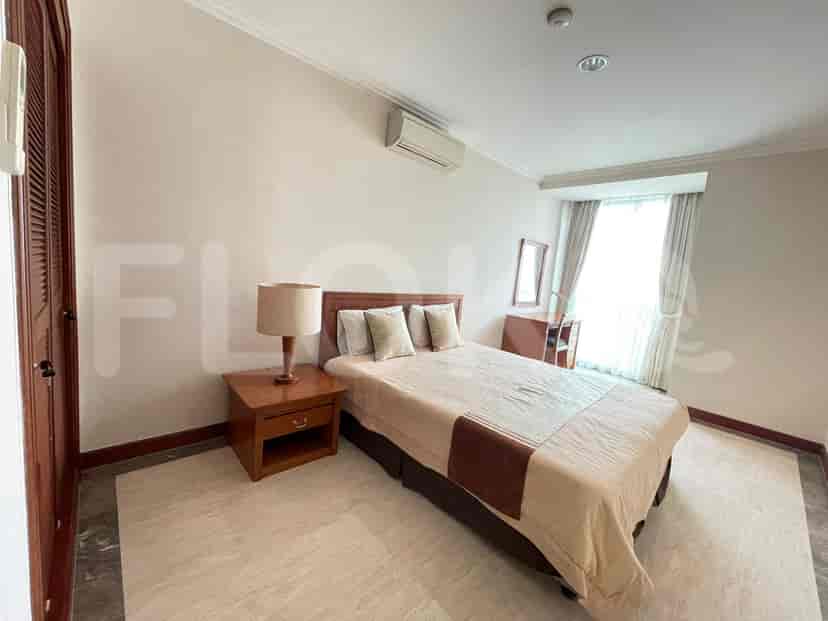 A bedroom with a single bed, bedside table, and air conditioning.