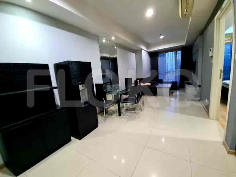 Modern living space with dining area, featuring black furniture, tile flooring, and a mirror wall.