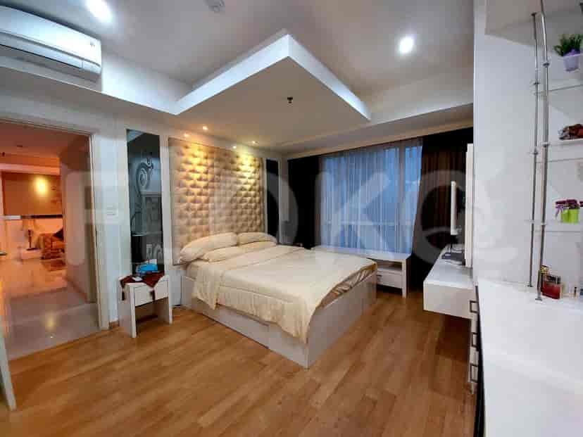 Bedroom featuring a bed with a padded headboard, side tables, and a window.