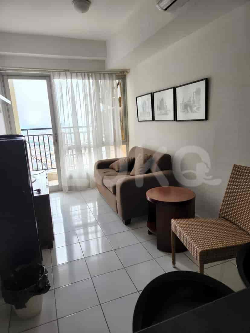 Living room with a sofa, a side table, and a balcony with sheer curtains.