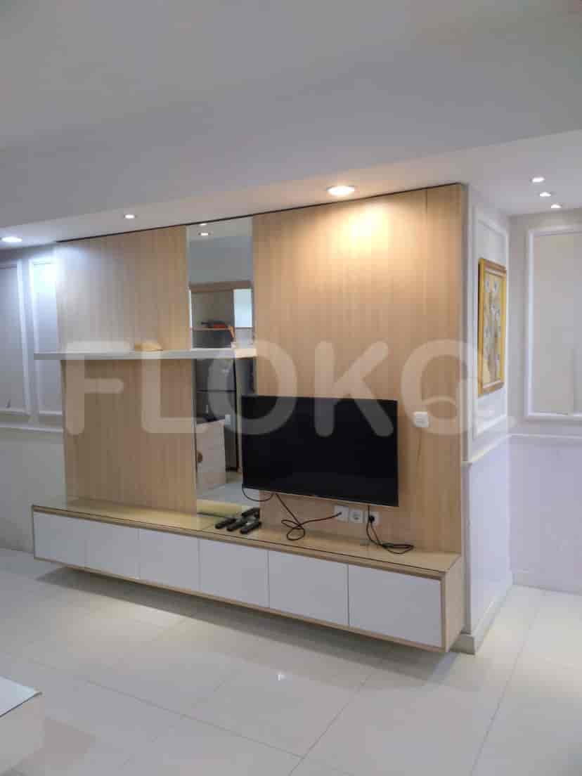 Living room with an entertainment unit, TV, and a mirrored wall.