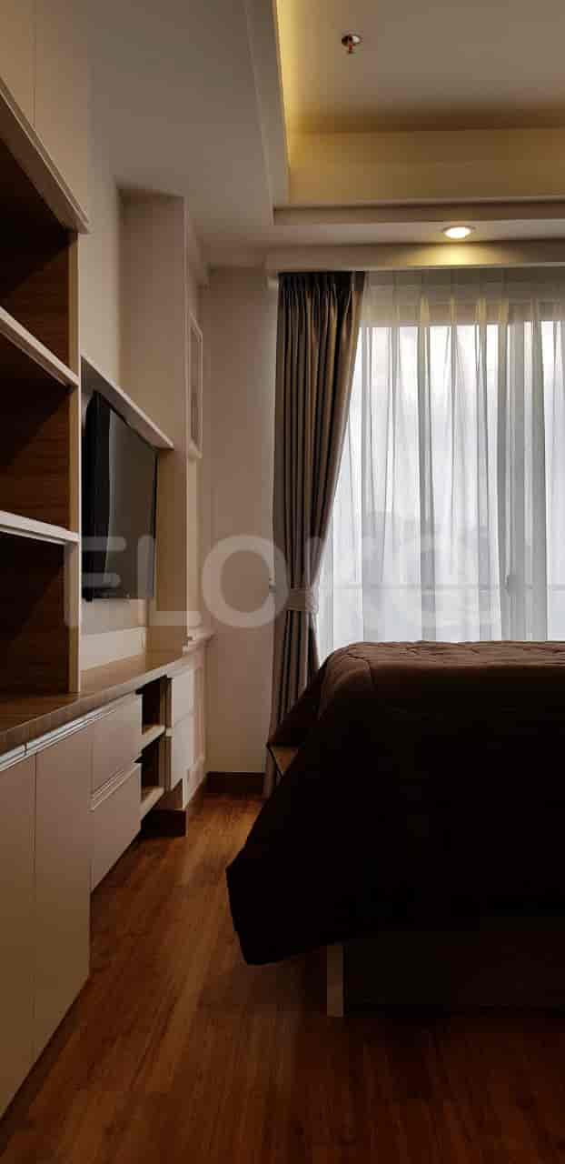 Bedroom with wooden flooring and curtains.