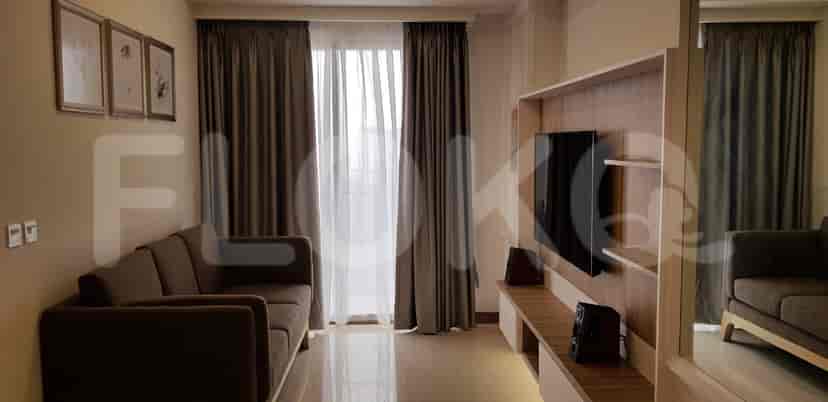 Spacious living room with a brown sofa, wall-mounted TV, and large windows.