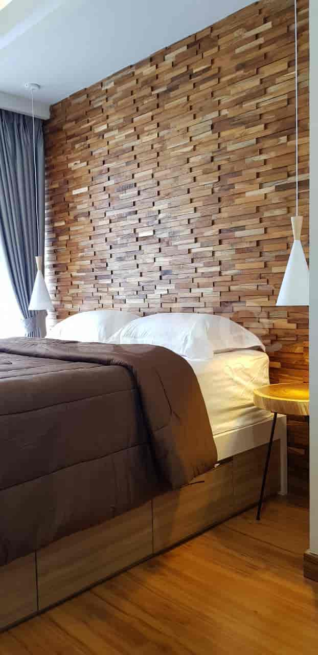Cozy bedroom with wooden accent wall, wooden flooring, and a bed.