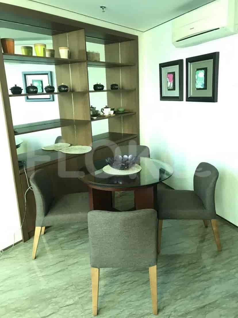 Area makan dengan meja bundar, kursi, dan rak built-in.