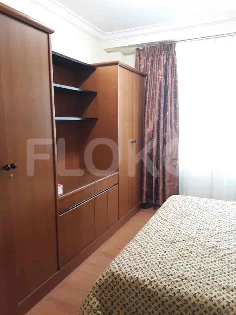 A bedroom featuring a large wooden wardrobe, bed, and curtains.