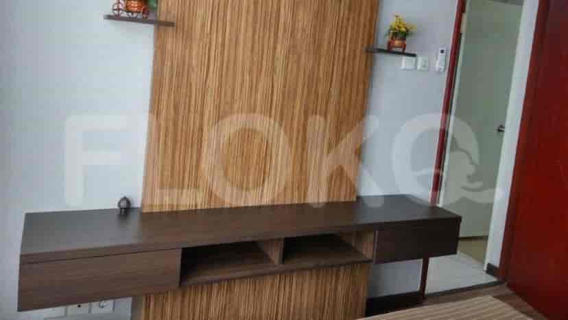 A wall with a TV, decor and storage.
