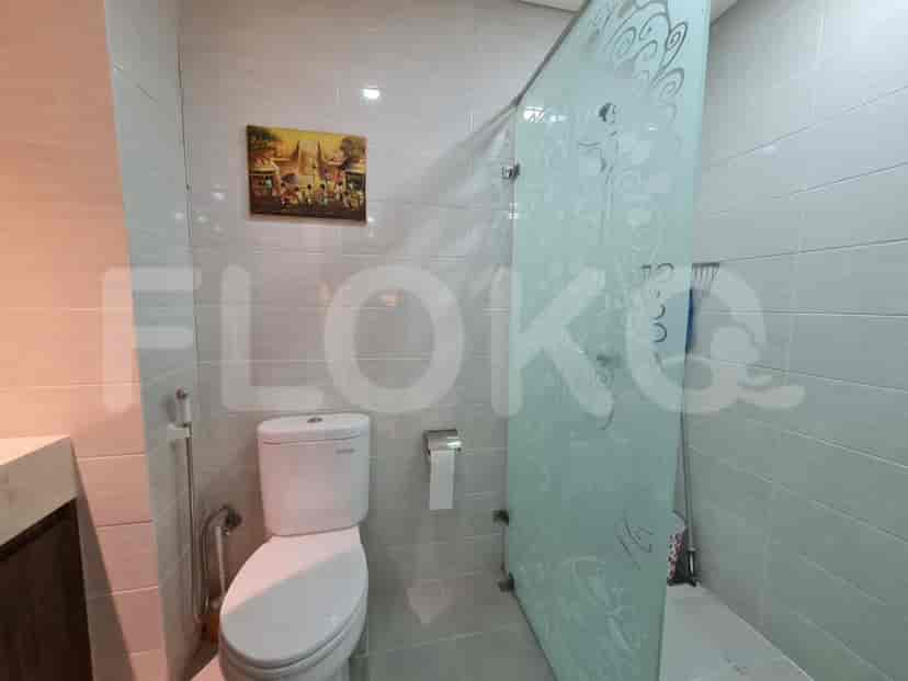 A compact bathroom with a toilet and a shower behind a glass partition.