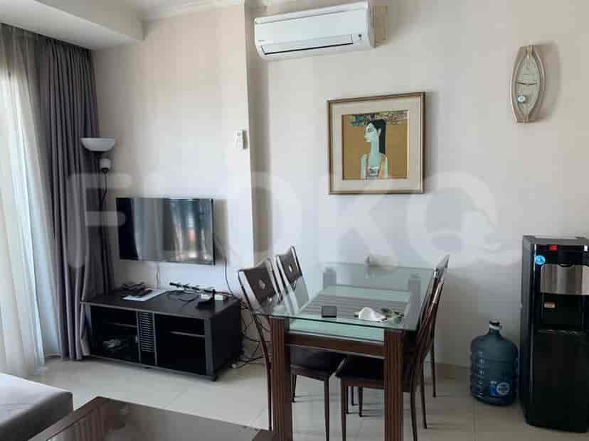 A well-lit living room with a dining area, featuring a TV, sofa, and dining table.