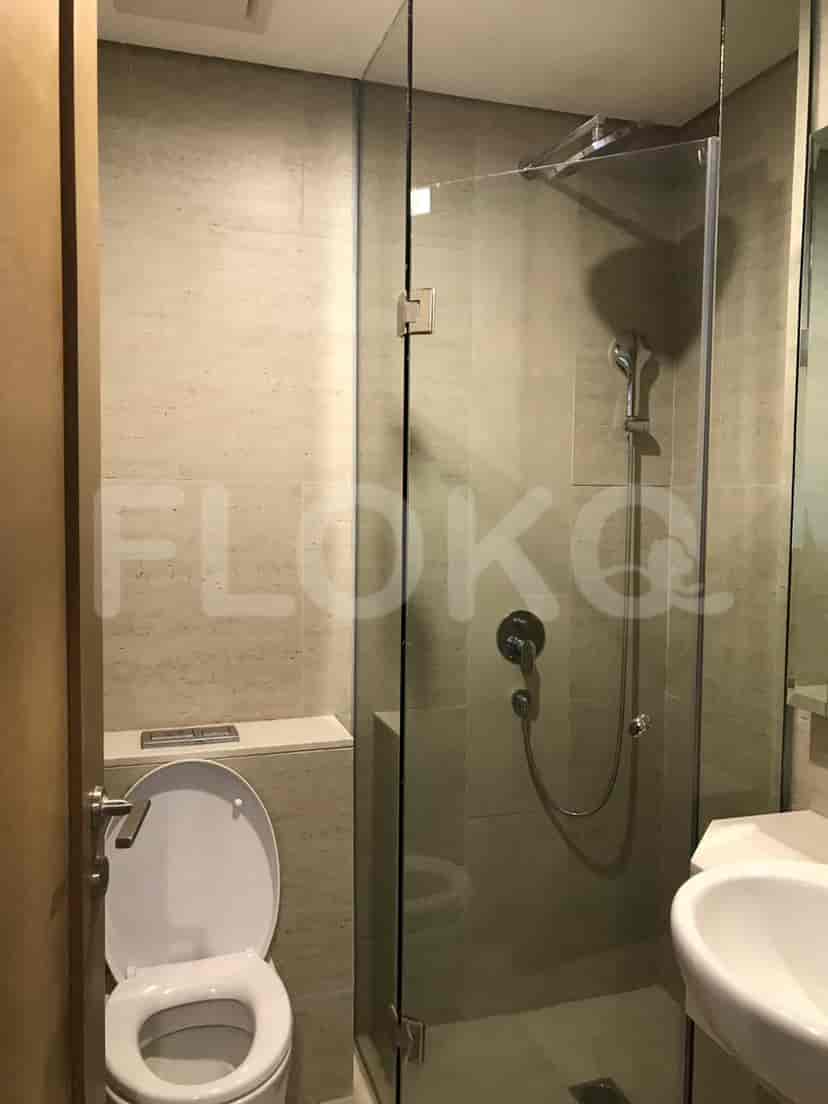 A modern bathroom with a glass shower enclosure, toilet, and sink.