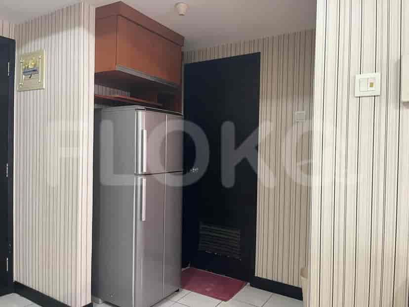 A kitchenette featuring a refrigerator, cabinets, and a door.