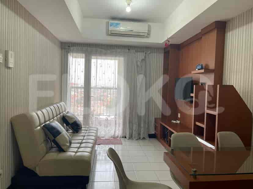 A living room with a sofa, TV, and balcony.