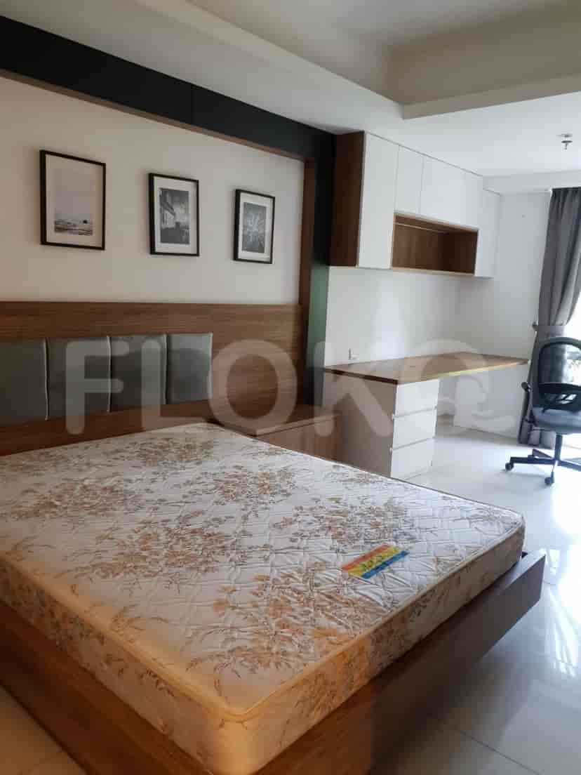 A cozy bedroom featuring a wooden bed frame, a patterned mattress, and framed artwork on the wall.