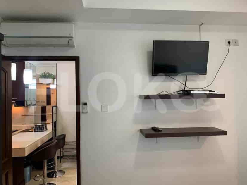 Living area with a mounted TV, floating shelves, and kitchen access.