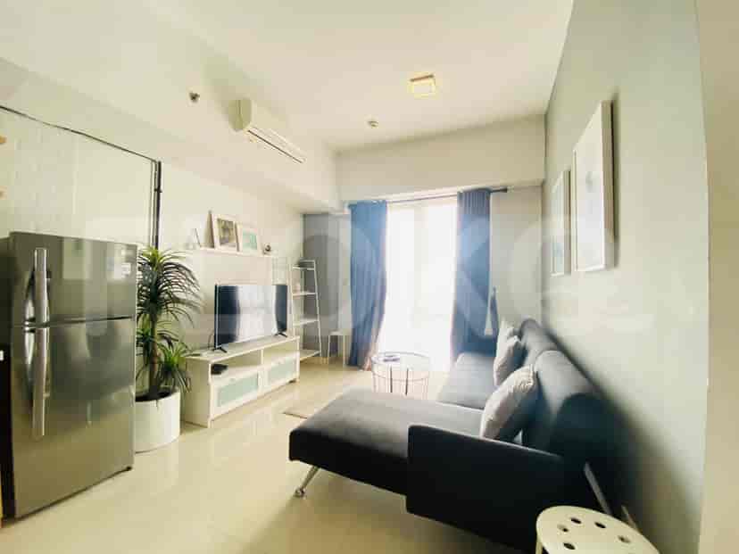 Ruang tamu modern dengan sofa abu-abu, TV, dan jendela.