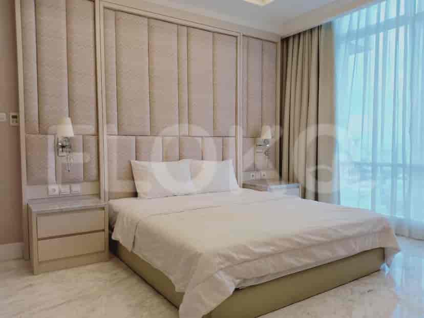 A bedroom featuring a bed with a tall cushioned headboard, side tables, and window.