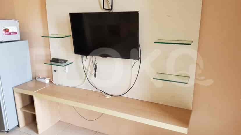 A room featuring a TV, shelves, and a small refrigerator.