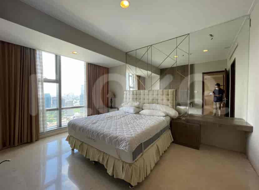 A modern bedroom with a king-sized bed, a large mirror, and a city view.