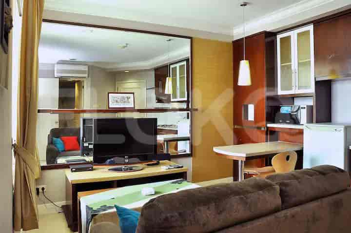 Combined living room and kitchenette area with a sofa, TV, and dining space, featuring a mirrored wall.