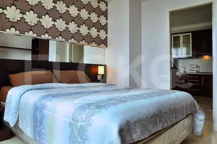A modern bedroom with a large bed, patterned wallpaper, and bedside lamps.