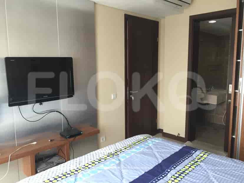 A bedroom with a wall-mounted TV, a wooden side table, and a double bed.